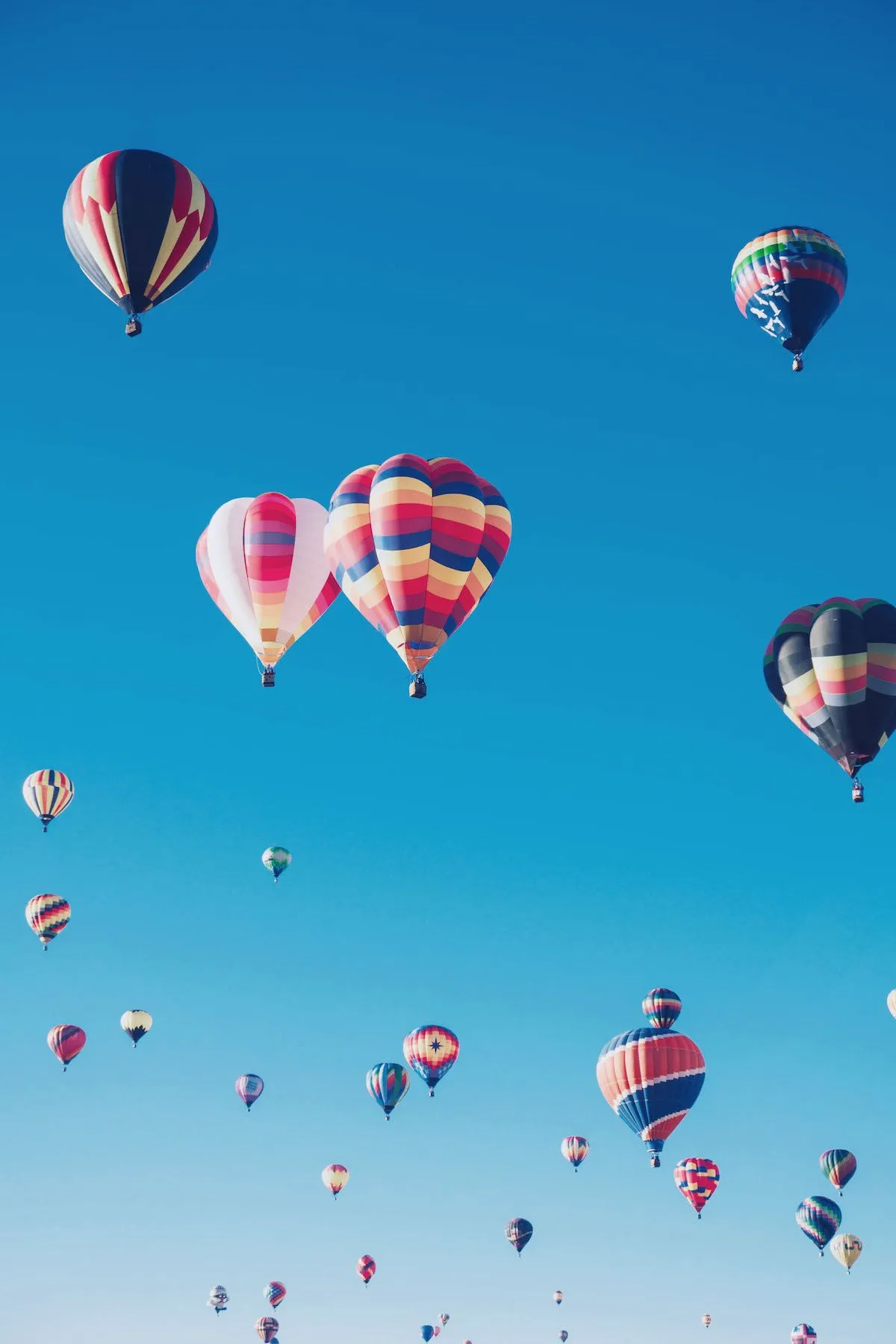 Mongolfiere colorate che si alzano in un cielo azzurro — la vita è un continuo viaggio